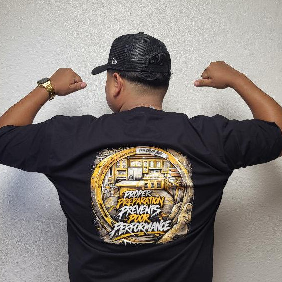 Person wearing a black t-shirt with a logo on the back, flexing muscles against a plain wall.