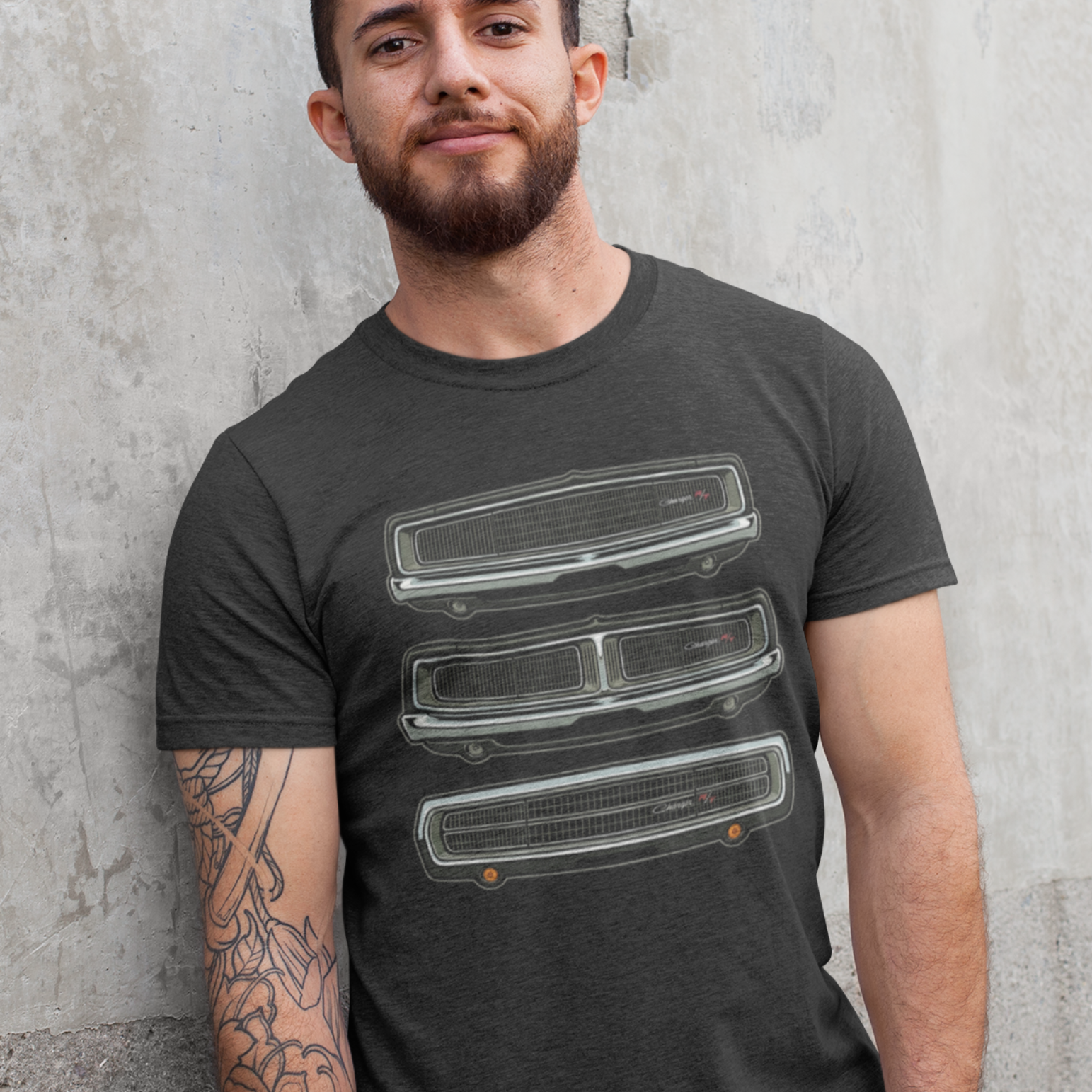 Man wearing a dark gray t-shirt with graphic design against a concrete wall.