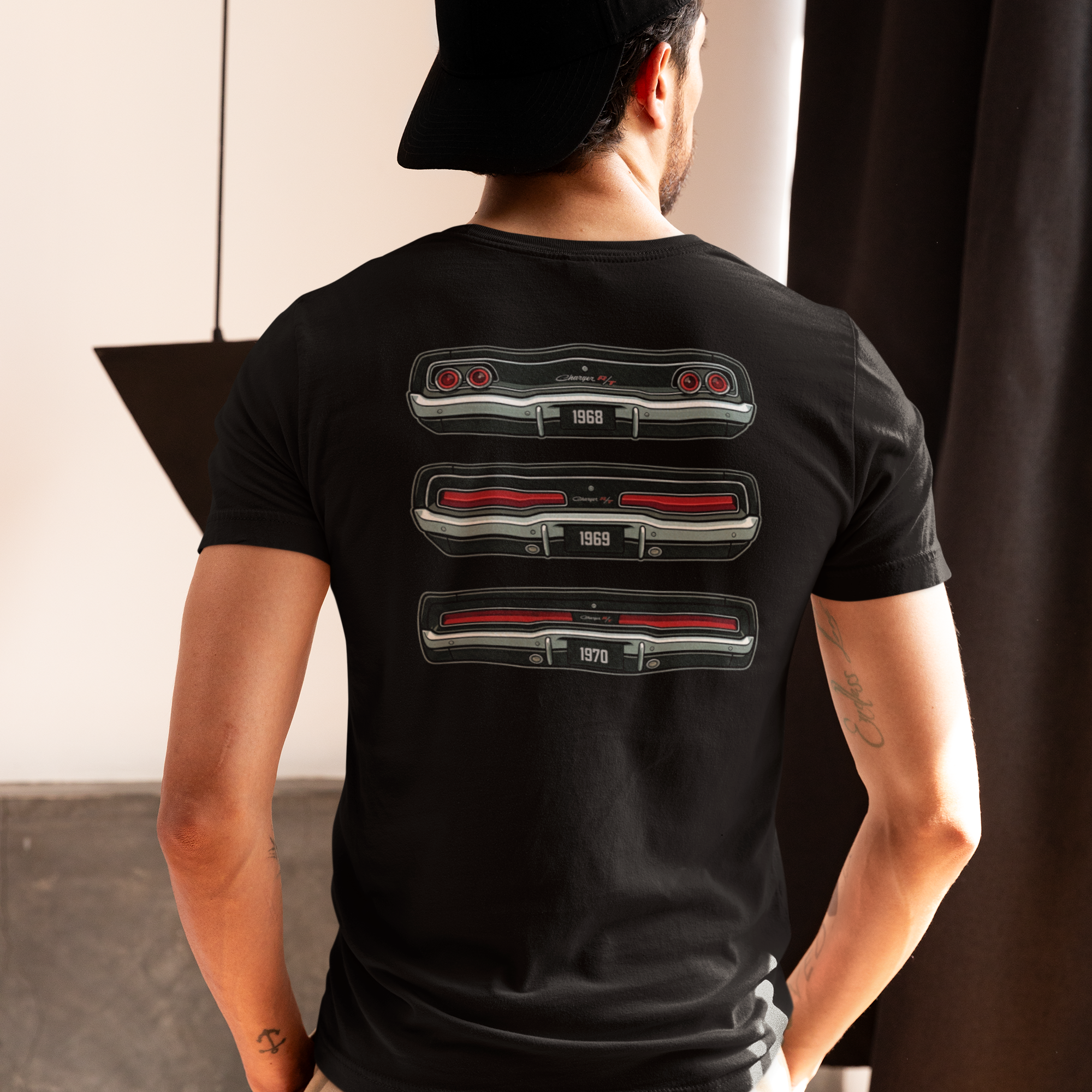 Person wearing a black t-shirt with a graphic design on the back, standing indoors.