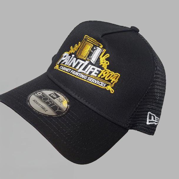 Black cap with 'PaintLife 1904' logo held by a hand against a gray background